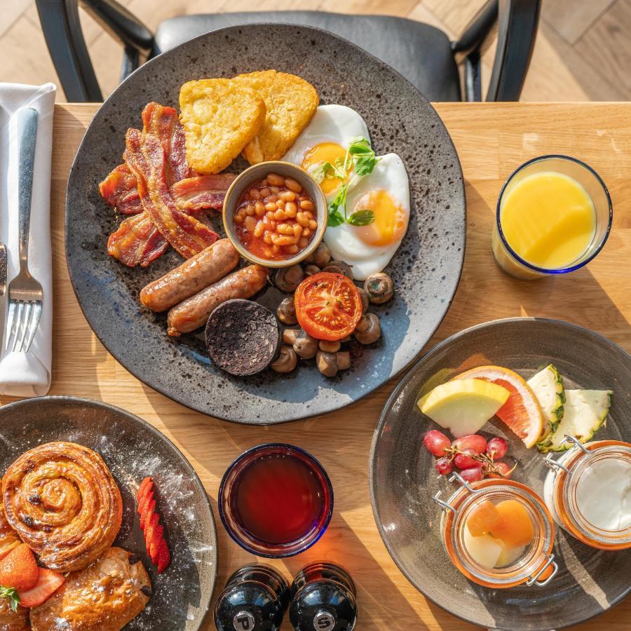 Citysuites 2 Aparthotel 索尔福德 外观 照片 The photo showcases a delicious breakfast spread. On a large, dark plate, there are items including crispy bacon, two fried eggs, baked beans, a grilled tomato, sautéed mushrooms, sausage links, and slices of black pudding. There's also a few pieces 