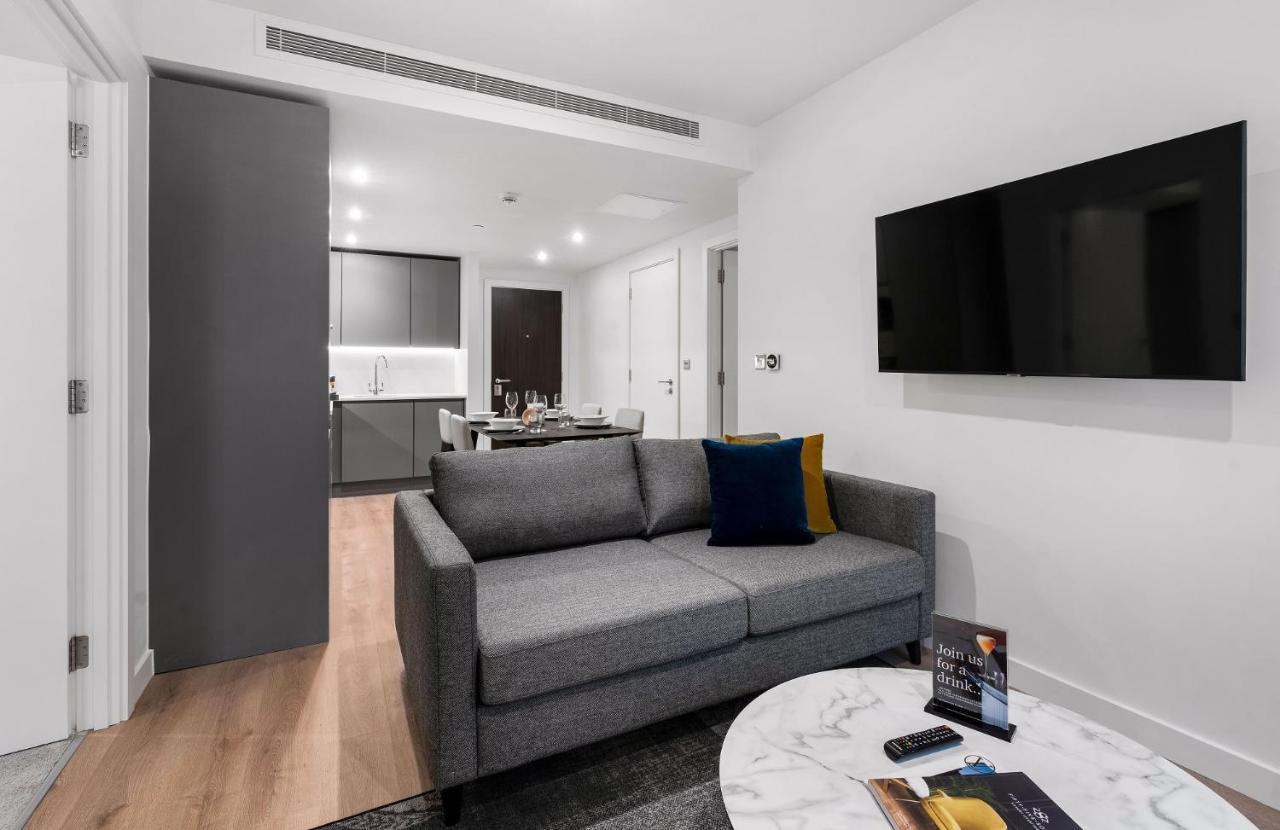 Citysuites 2 Aparthotel 索尔福德 外观 照片 The photo shows a modern living space that includes a gray sofa with colorful cushions, a round marble coffee table, and a flat-screen TV mounted on the wall. In the background, there is a kitchen area featuring sleek cabinets. The flooring is light 