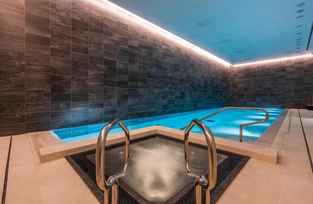 Citysuites 2 Aparthotel 索尔福德 外观 照片 The photo shows a modern indoor swimming pool area. The pool features a sleek, rectangular design with a beautiful blue water that seems illuminated. Surrounding the pool are dark, textured walls, adding to the elegant atmosphere. There are dual meta
