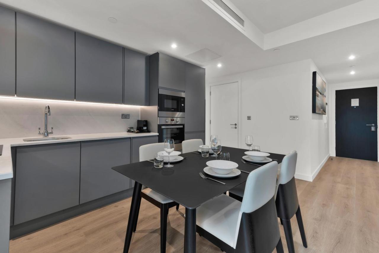 Citysuites 2 Aparthotel 索尔福德 外观 照片 The photo shows a modern kitchen and dining area. There are sleek gray cabinetry and countertops, with a built-in oven and microwave. The kitchen is well-lit, featuring under-cabinet lighting that adds to the contemporary feel. In the dining area, th