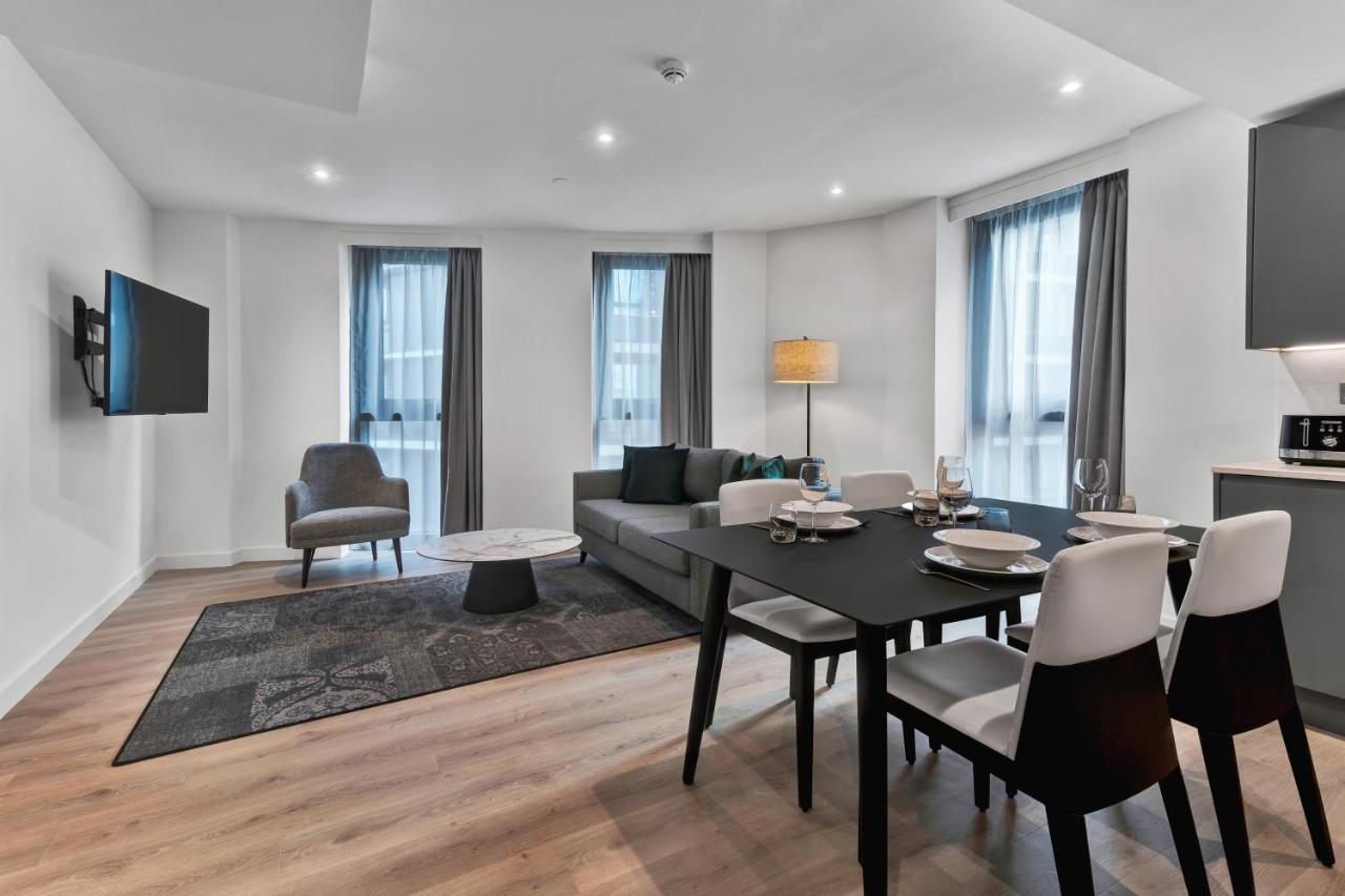 Citysuites 2 Aparthotel 曼彻斯特 外观 照片 The photo shows a modern living space that includes a living area and dining area. 

- **Living Area**: There's a gray sofa with a coffee table in front of it, along with a single armchair. A large flat-screen TV is mounted on the wall. The space is 