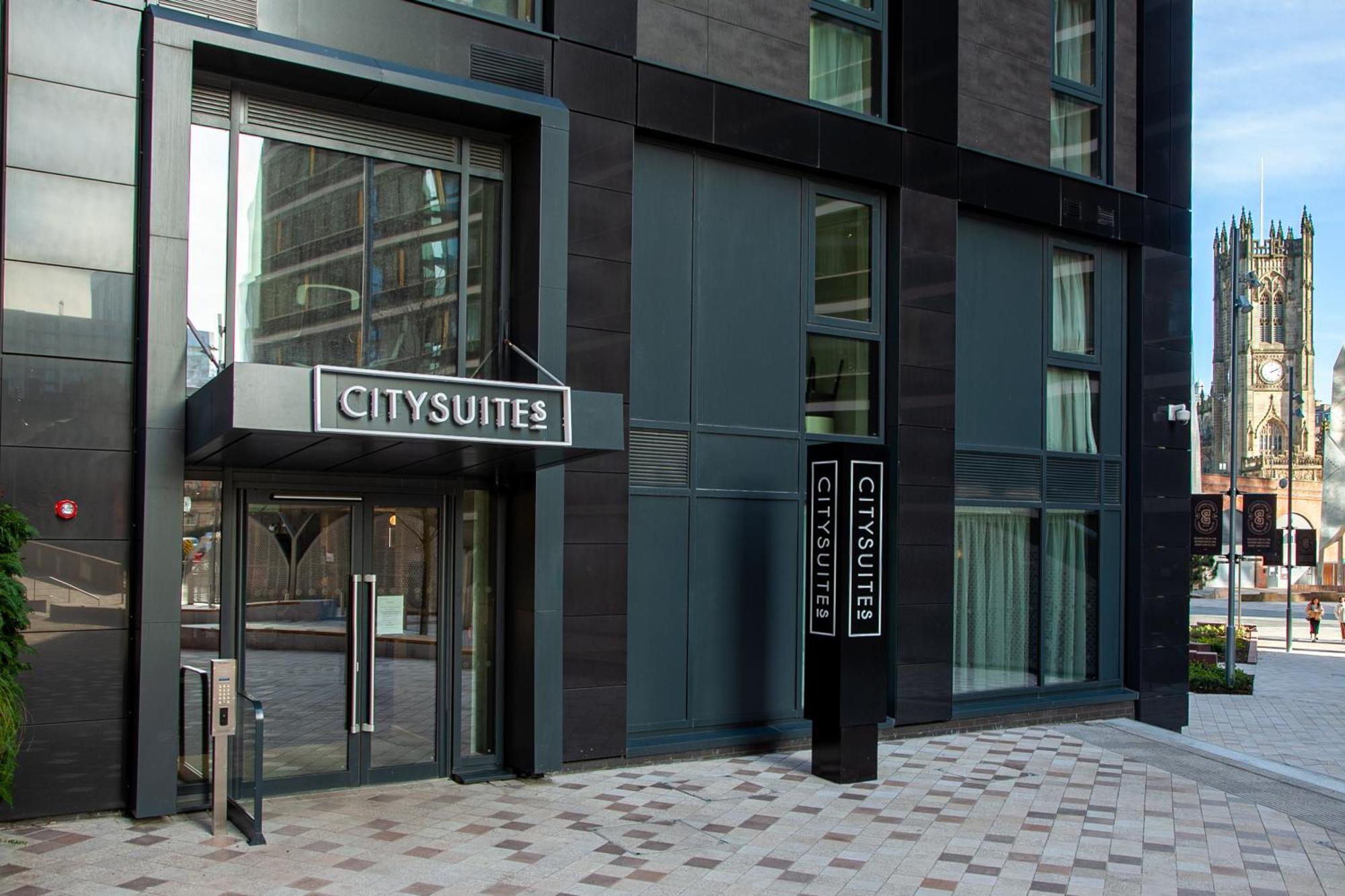 Citysuites 2 Aparthotel 曼彻斯特 外观 照片 The photo shows the entrance to a modern building labeled "CITYSUITES." The entrance features large glass doors and a sleek, contemporary design. The building has dark exterior panels and large windows, suggesting a stylish and urban environment. The