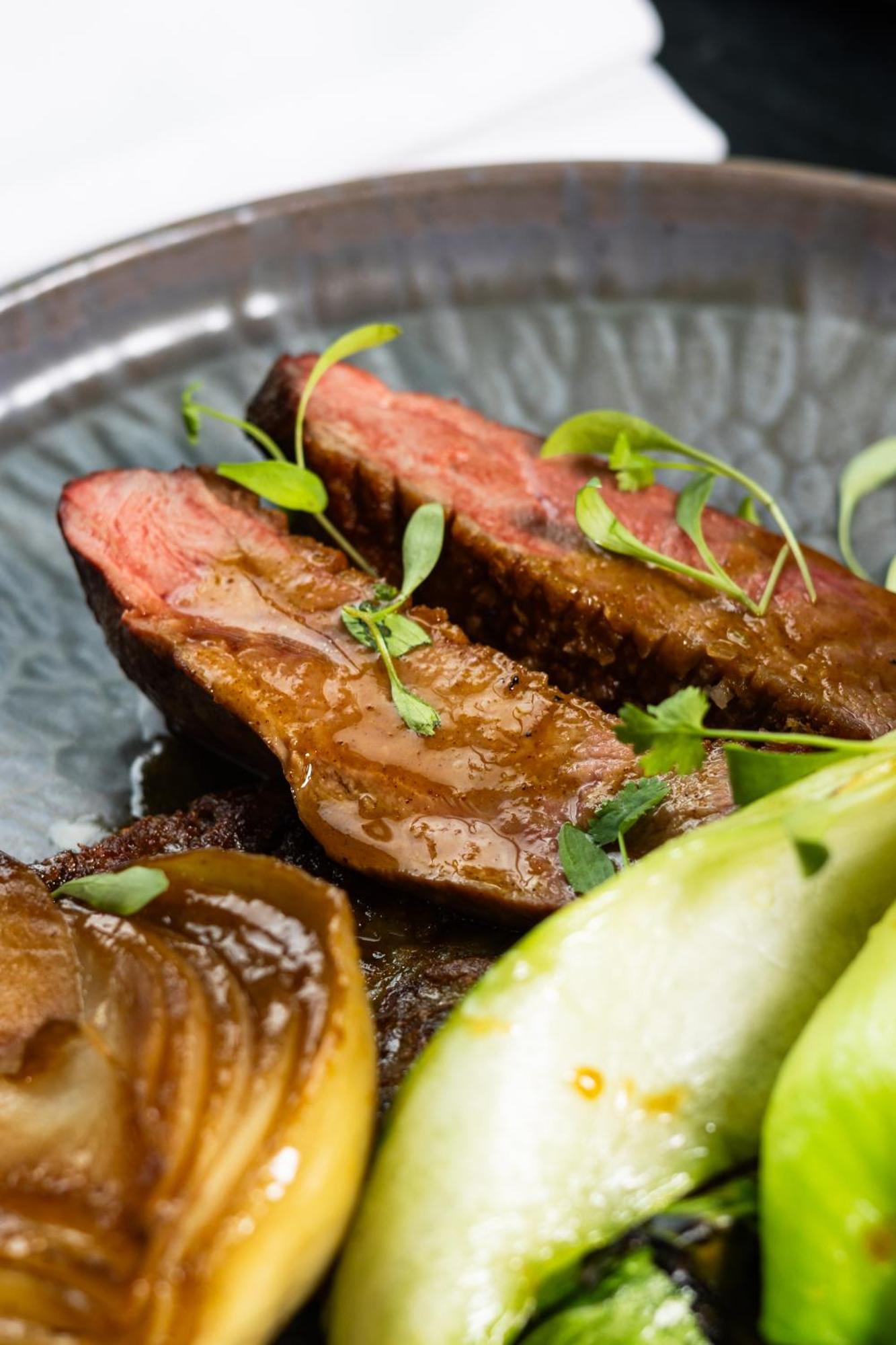 Citysuites 2 Aparthotel 曼彻斯特 外观 照片 The photo features slices of meat, likely beef, presented on a decorative plate. The meat appears to have a rich brown sauce drizzled over it and is garnished with fresh herbs, adding a pop of green. There are also some slices of a light-colored vege