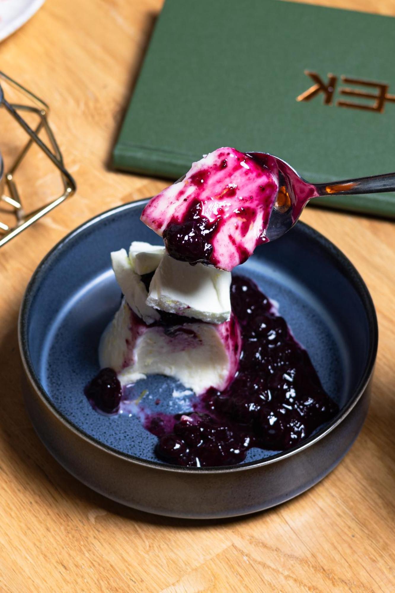 Citysuites 2 Aparthotel 索尔福德 外观 照片 The photo shows a serving of dessert, likely a type of panna cotta or a creamy custard, partially dished out and accompanied by a rich berry sauce, possibly made from blueberries or blackberries. A spoon with some of the dessert and sauce is hovering